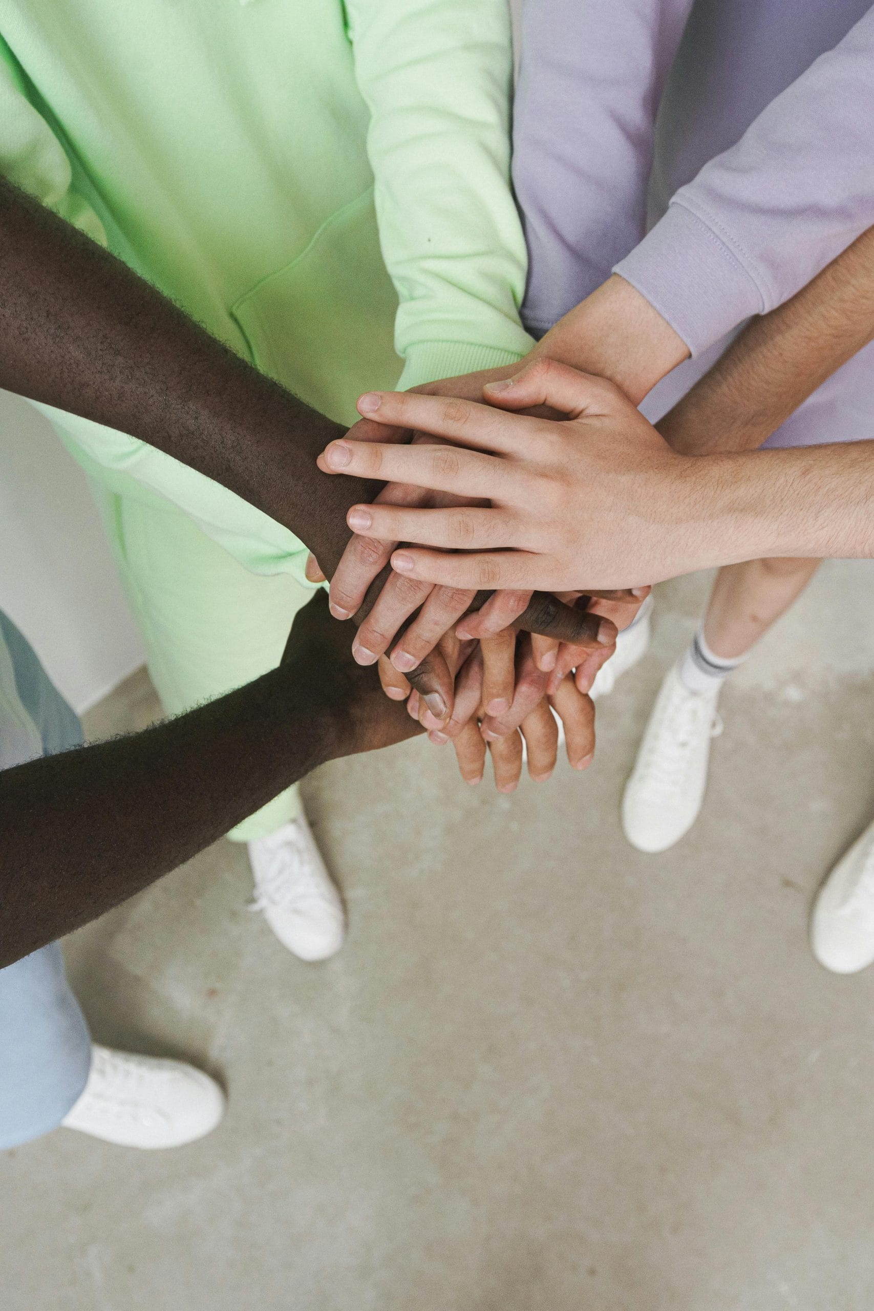 Top view of diverse hands joined together in a gesture of unity and teamwork.